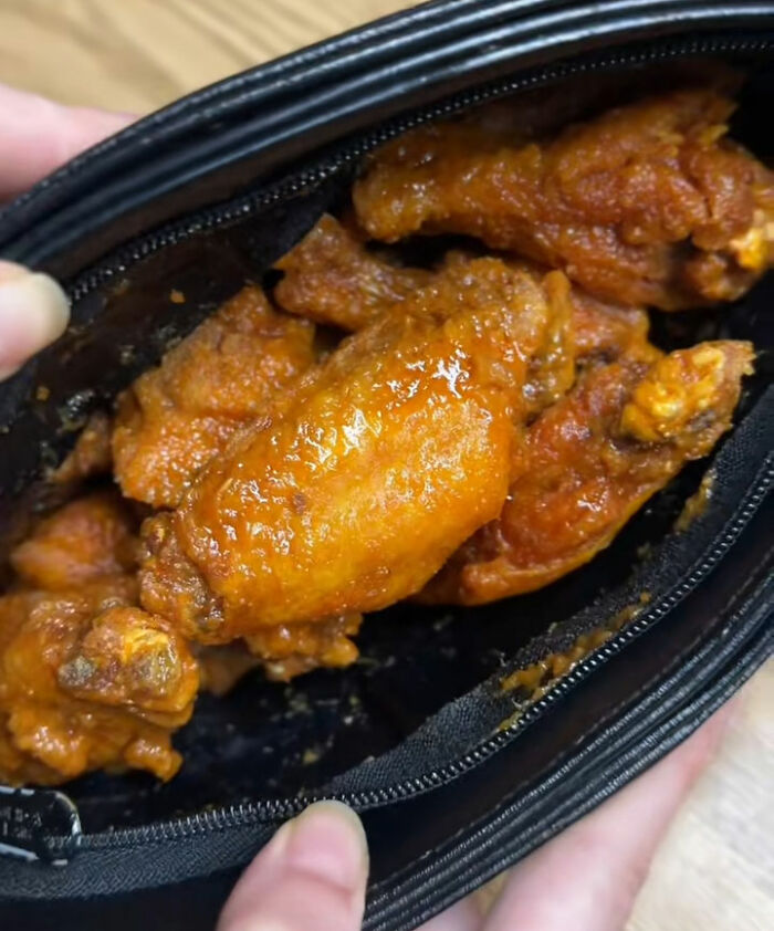 Buffet employees' disgusting display of gluttony with greasy chicken wings inside a zipped black container.