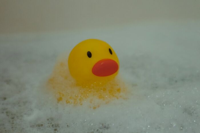 Yellow rubber duck floating in foam bubbles, illustrating common daily dangers you might not realize.