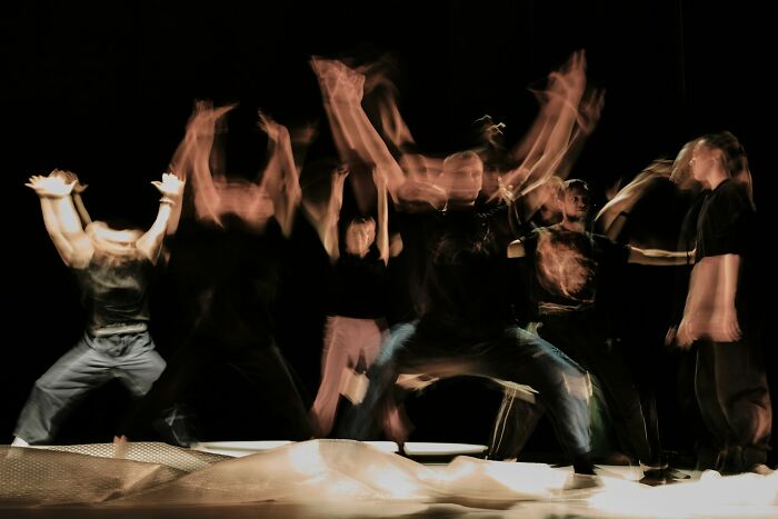 Blurred group of people moving energetically on stage, representing former cult members experiencing a moment of realization.