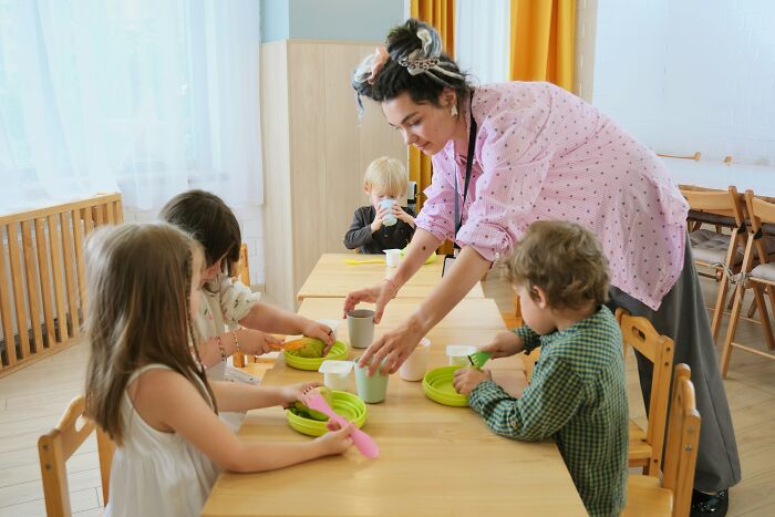 Teacher serving children at a daycare table, illustrating moments people realized they no longer wanted to work.