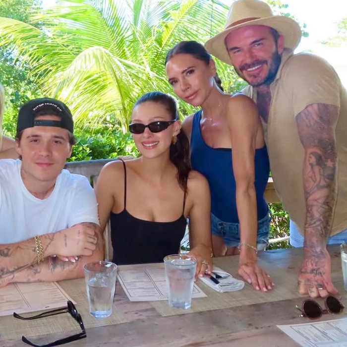 Victoria Beckham and Nicola Peltz posing together with two others at a table outdoors during a casual outing. Victoria Beckham and Nicola Peltz posing together with two others at a table outdoors during a casual outing.