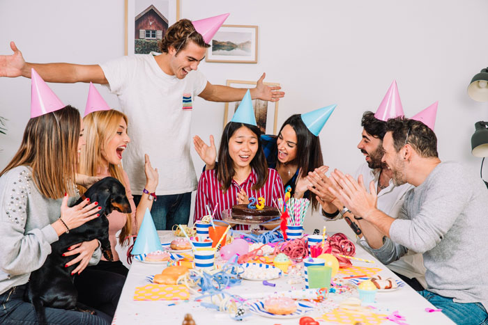 Family celebrating a birthday with party hats, a cake, and a camera capturing moments with an aunt present.
