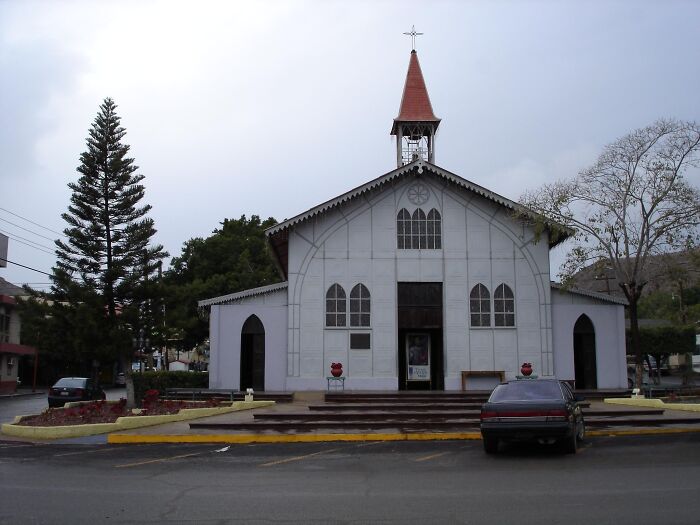 White church with a red steeple in front of trees and parked cars, illustrating lesser-known facts about countries.