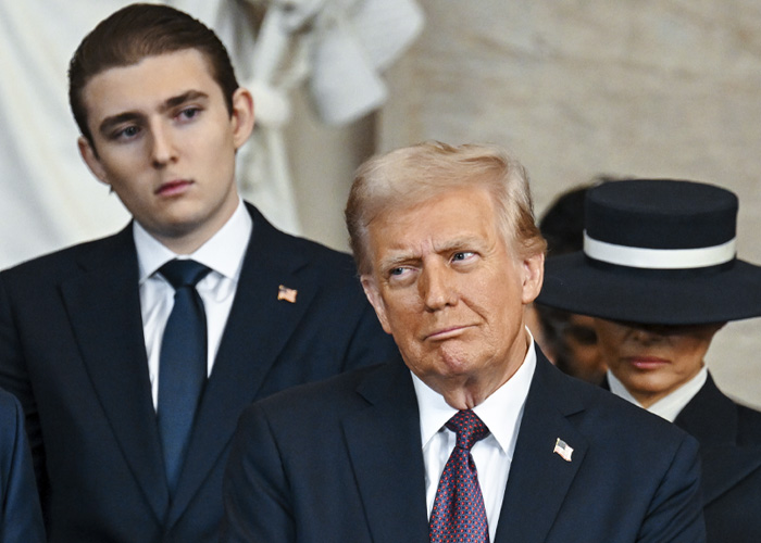 Barron Trump standing behind Donald Trump at an event, highlighting an awkward moment linked to paternity conspiracy theories. Barron Trump standing behind Donald Trump at an event, highlighting an awkward moment linked to paternity conspiracy theories.