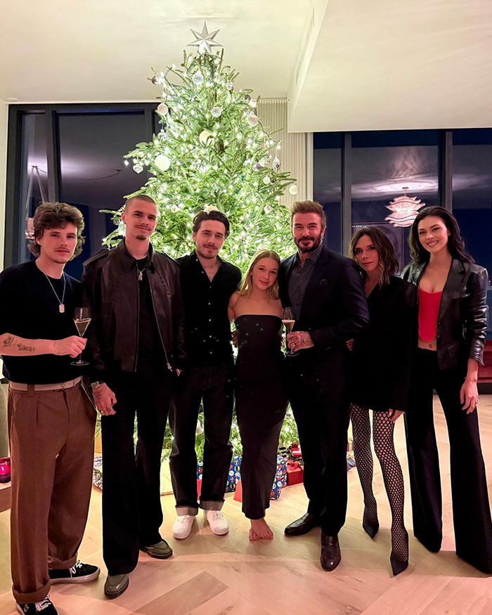 Brooklyn Beckham with family by decorated Christmas tree during a festive gathering at home.