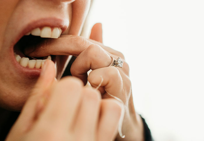 Person flossing teeth close-up, demonstrating easy skills to improve your life and personal care habits.