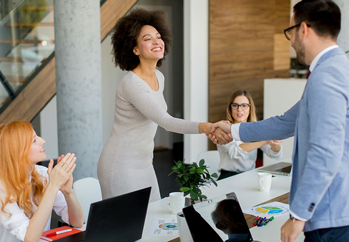 A diverse group of professionals shaking hands and discussing easy skills to improve life in a modern office setting.