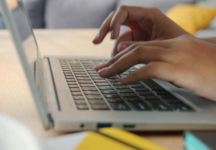 Hands typing on a laptop keyboard, illustrating easy skills to improve your life for a rich retirement.