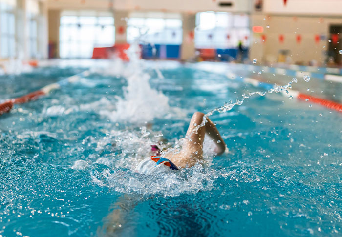 Person swimming in an indoor pool practicing easy skills to improve life and promote a healthy lifestyle.