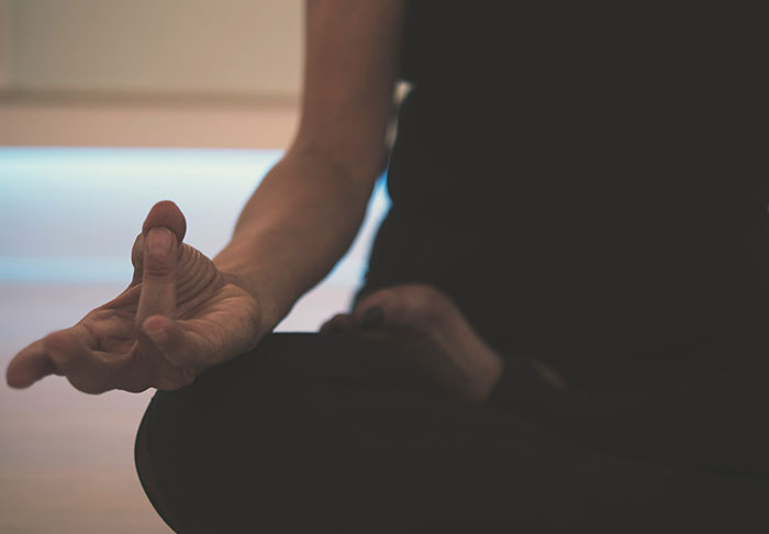 Person practicing meditation in a dim room, focusing on easy skills to improve life and retire rich.