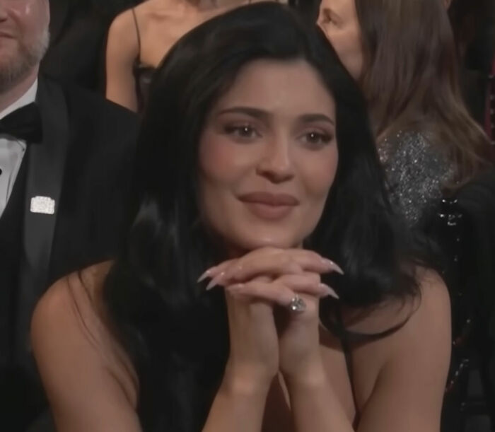 Woman with long black hair and manicured nails sitting at an event, related to video of Timothée Chalamet using Kylie's BBL. Woman with long black hair and manicured nails sitting at an event, related to video of Timothée Chalamet using Kylie's BBL.