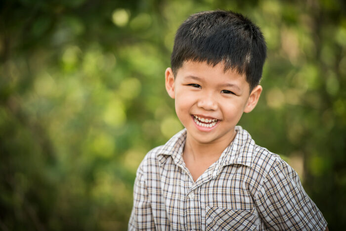 Young bilingual boy smiling outdoors, representing weird and awkward instances of catching someone gossiping.