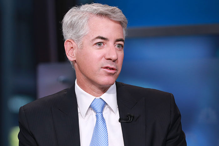 Bill Ackman in a dark suit and blue tie speaking about billionaires and a controversial ICE agent donation.