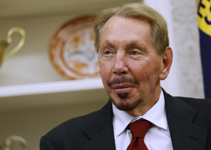 Portrait of a billionaire in a suit and red tie, related to a story about a boat name change after backward spelling was noticed.