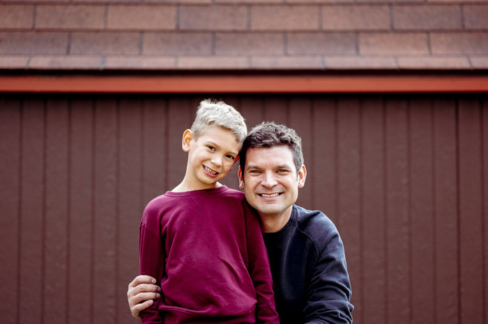 Teen boy and man smiling together outdoors, representing teen refusing to live with bio parents in a court dispute.