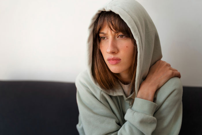 Teen girl in a hoodie looking hurt and contemplative, reflecting feelings about bio mom and relationship expectations.