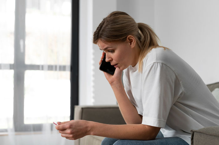 Woman in casual clothes looking worried while talking on phone, illustrating bio mom and relationship struggles. Woman in casual clothes looking worried while talking on phone, illustrating bio mom and relationship struggles.