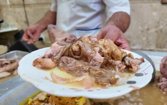 Plate of unusual local delicacy featuring cooked animal parts served in broth, showcasing disgusting local delicacies from various countries.