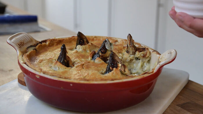 Bizarre local delicacy pie with fish heads poking out, showcasing unusual and disgusting food from different countries.