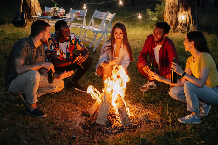Group of friends laughing and sharing stories around a campfire, capturing a playful bullying and breakup moment. Group of friends laughing and sharing stories around a campfire, capturing a playful bullying and breakup moment.