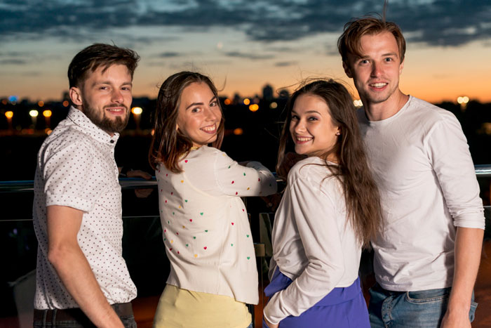 Four young adults smiling together outdoors at sunset, capturing a moment linked to childhood trauma and family tradition. Four young adults smiling together outdoors at sunset, capturing a moment linked to childhood trauma and family tradition.