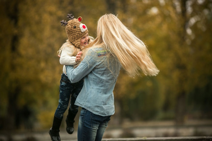 Woman holding child wearing reindeer hat outdoors, reflecting Christmas tradition and childhood trauma themes. Woman holding child wearing reindeer hat outdoors, reflecting Christmas tradition and childhood trauma themes.