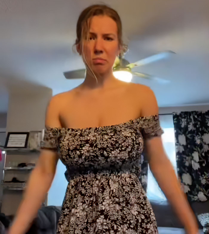 Woman with serious expression wearing floral dress after viral breast reduction, facing online trolling from men. Woman with serious expression wearing floral dress after viral breast reduction, facing online trolling from men.