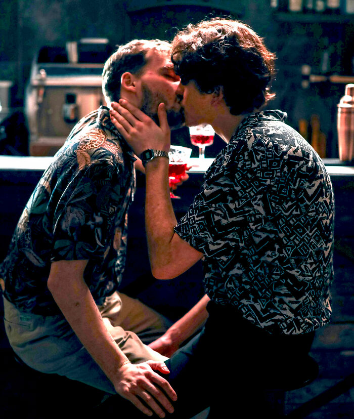 Two men kissing closely in a dimly lit nightclub, capturing the wild party stories and unique nightclub atmosphere.