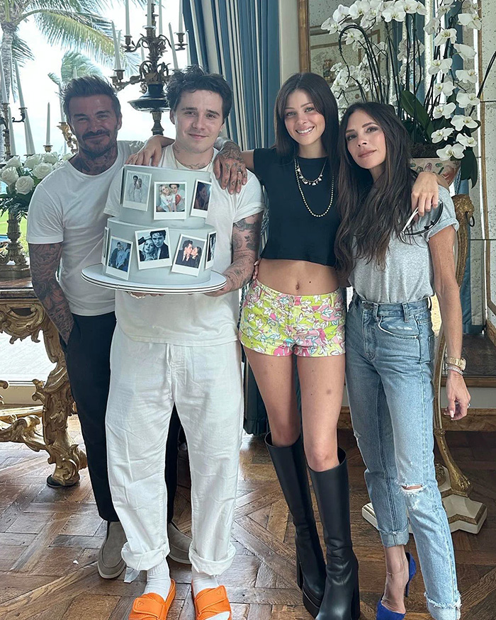 Brooklyn Beckham holding a photo cake with family members David and Victoria amid family drama.