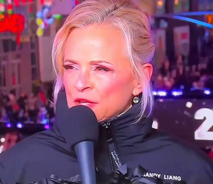 Amy Sedaris speaking into a microphone during CNN New Year's Eve broadcast with colorful crowd and lights in background. Amy Sedaris speaking into a microphone during CNN New Year's Eve broadcast with colorful crowd and lights in background.