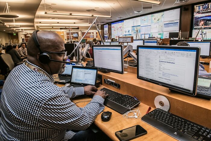 Man with headset working on multiple computer screens in an office, revealing dramatic behind scenes of people in boring industries.