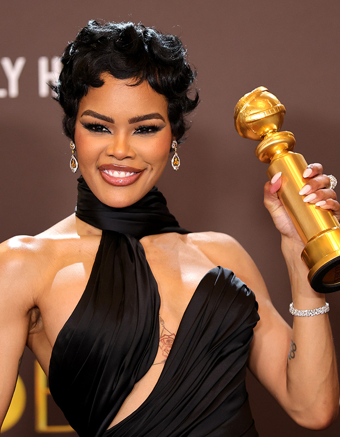 Smiling woman in elegant black dress holding Golden Globe trophy, showcasing celeb facialist secrets for radiant glow.