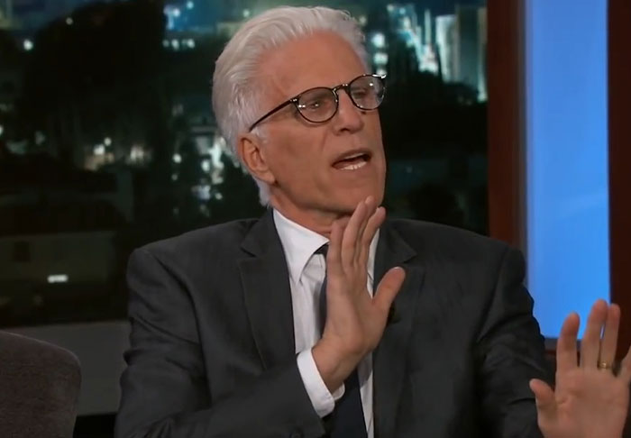 Older man with white hair and glasses speaking and gesturing with hands during a late night talk show interview about celebrity infidelity scandals.