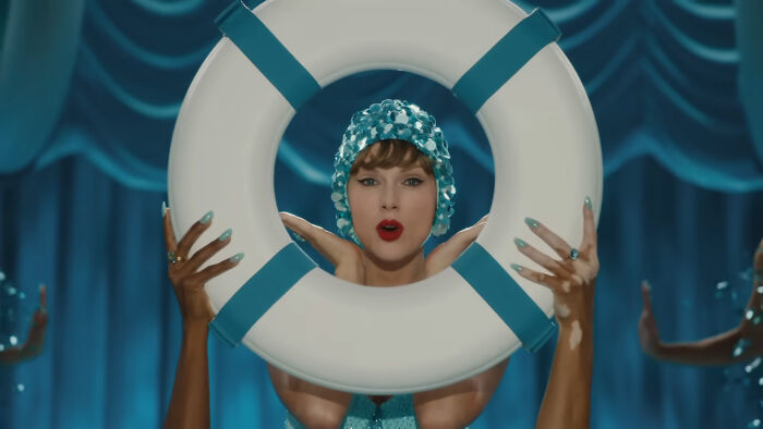 Taylor Swift in a vintage swim cap holding a life preserver, representing savage responses from celebs to intrusive questions.