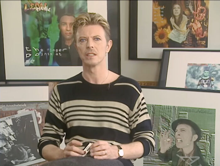 David Bowie in a casual interview setting, responding to annoying or invasive questions with a composed expression.
