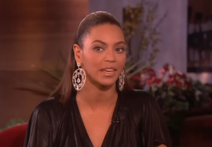 Celebrity wearing large earrings and a black top during an interview showing out of touch with reality moments.