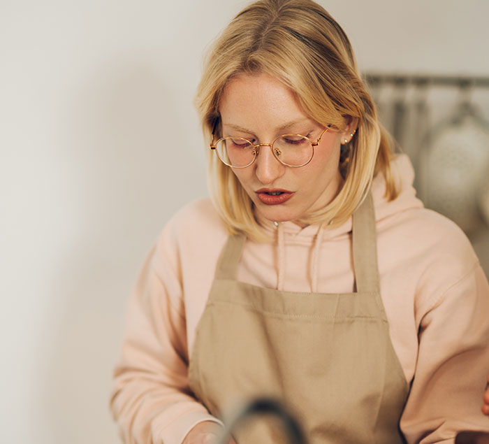 Blonde female chef wearing glasses and an apron, focusing on cooking indoors, avoiding restaurants with boyfriend or girlfriend Blonde female chef wearing glasses and an apron, focusing on cooking indoors, avoiding restaurants with boyfriend or girlfriend