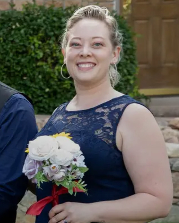 Smiling woman in navy lace dress holding a bouquet of flowers, related to ICE video and fatal shooting context. Smiling woman in navy lace dress holding a bouquet of flowers, related to ICE video and fatal shooting context.
