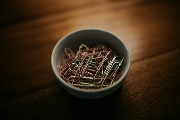 Bowl filled with colorful paperclips on a wooden table, symbolizing high school controversies and unexpected events.