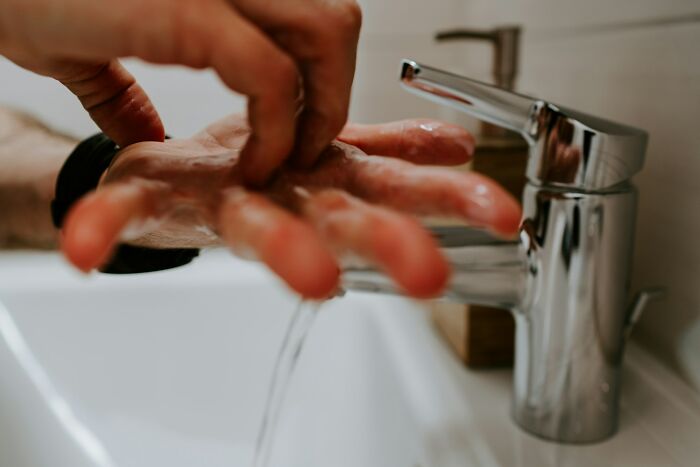 Hands being washed under a modern faucet with running water, illustrating simple solutions and everyday problems.