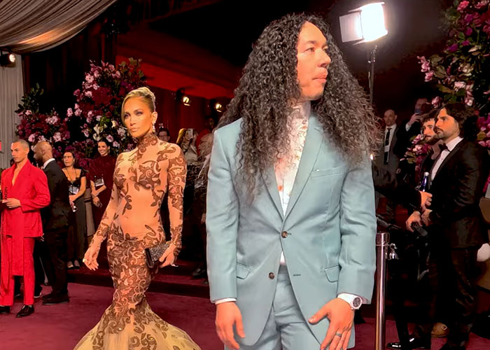 GlamBOT King in a light blue suit with long curly hair at the Golden Globes amid viral interaction with Jennifer Lopez.