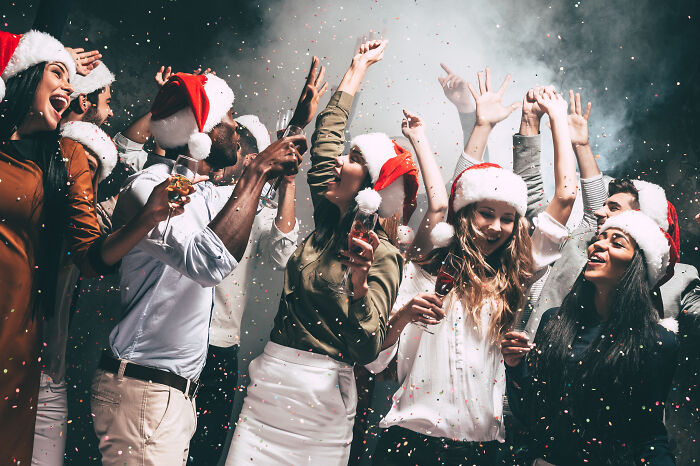 Group of people wearing Santa hats celebrating with drinks, highlighting a woman’s actions sparking a double-standard debate. Group of people wearing Santa hats celebrating with drinks, highlighting a woman’s actions sparking a double-standard debate.