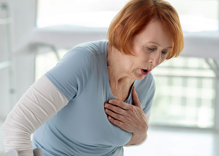 Older woman clutching her chest and gasping, depicting health signs of chest pain and shortness of breath