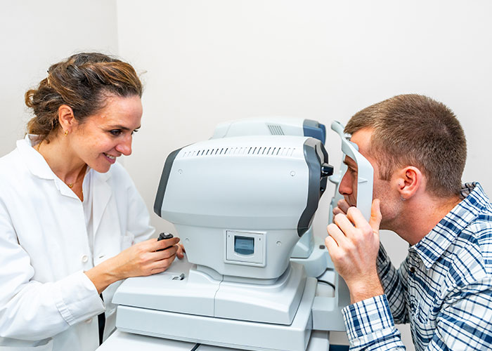Optometrist using an autorefractor on a patient during eye exam, illustrating health signs of potential eye issues