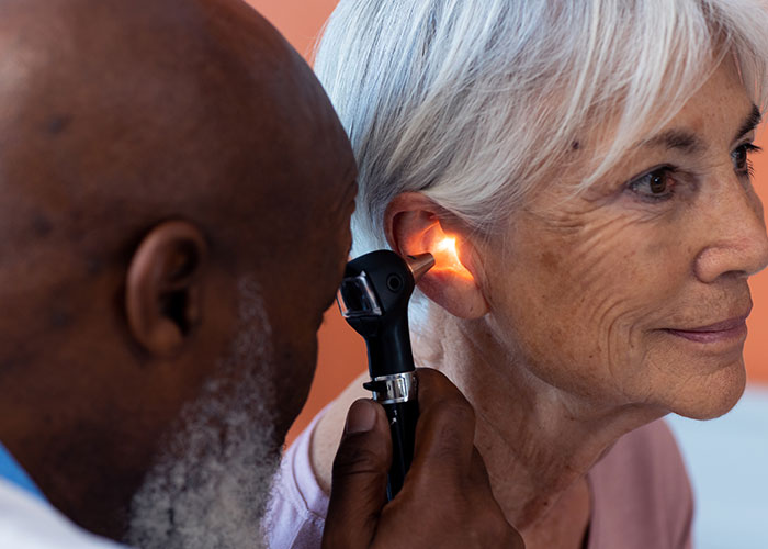 Doctor examining elderly woman's ear with otoscope, highlighting health signs to watch for