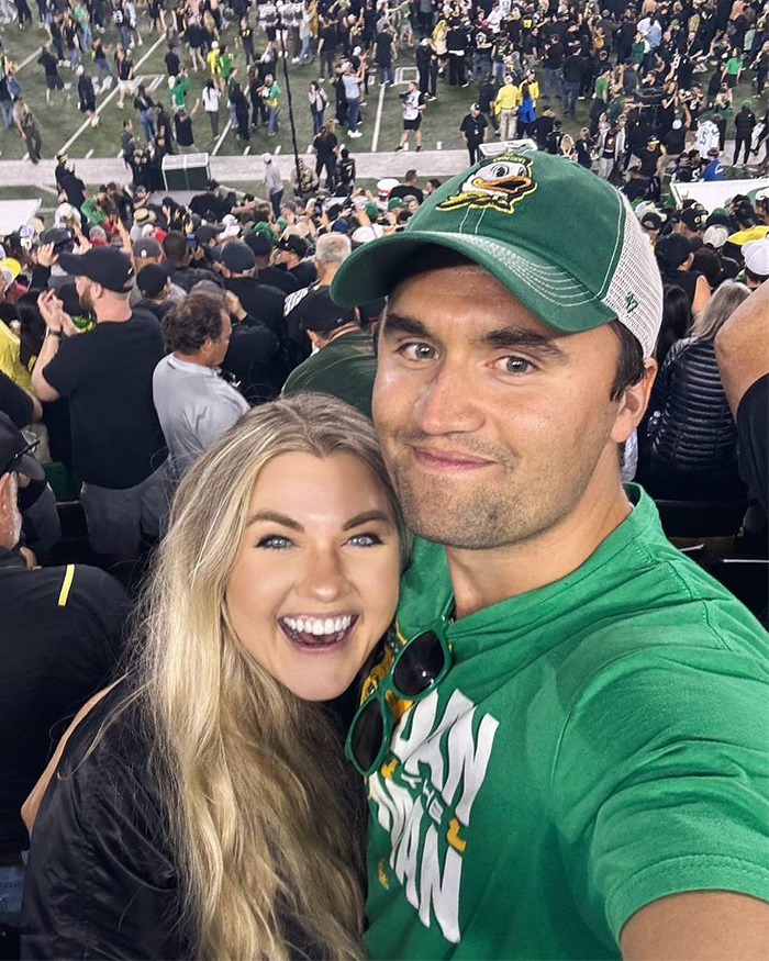Erika Kirk smiling with a man at a crowded sports event, capturing a selfie amid custody speculation buzz.