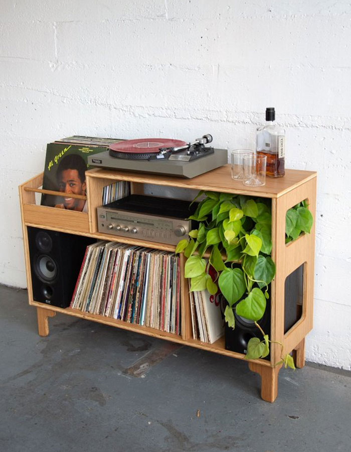 Modern wooden record player stand with speakers, vinyl collection, and greenery, showcasing cool interior design ideas.