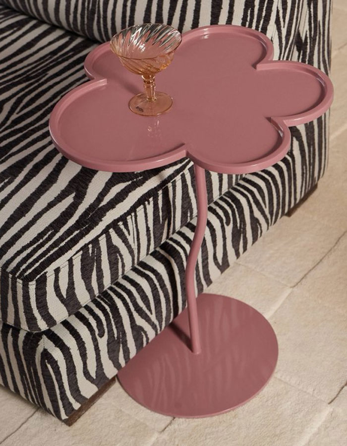Pink flower-shaped side table with a glass on top next to a zebra print sofa, showcasing cool interior design ideas.