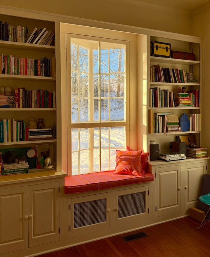 Cozy window seat with built-in bookshelves and warm lighting, showcasing cool interior design ideas for a stylish home.