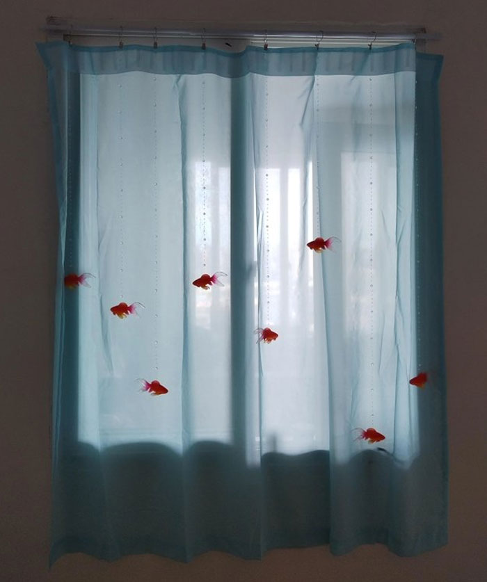 Translucent blue curtains with hanging decorative fish creating a cool interior design idea for a modern home.